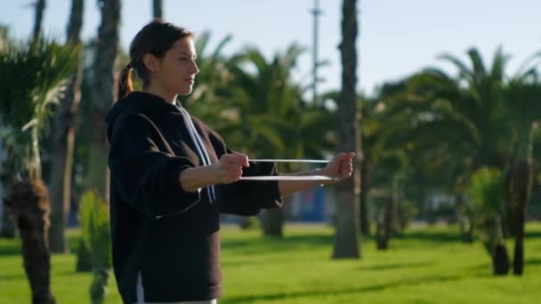 Женщина делает дыхательные упражнения и растягивает спортивную ленту в саду — стоковое видео