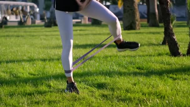 Sport utomhus, kvinna tränar ben med tejp — Stockvideo