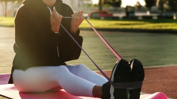 Entrenamiento de fitness al aire libre con banda elástica, la mujer se estira con las manos — Vídeos de Stock