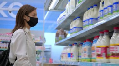 Yüz maskeli kadın süpermarketten süt alıyor.