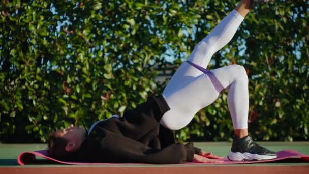 Тренер по фитнесу с резиновым спортивным поясом тренирует ее ягодицы — стоковое видео