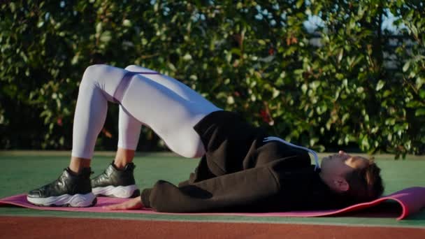 Sportig dam träning på golvet på matta och gör bridge motion för att tona muskler — Stockvideo