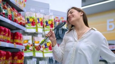 Komik kadın şakacı bir şekilde süpermarkette şarkı söylüyor.