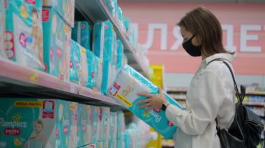 Rusya, Soçi - 20 Aralık 2020: Salgın sırasında hipermarketten alışveriş, anne bebek bezi seçiyor