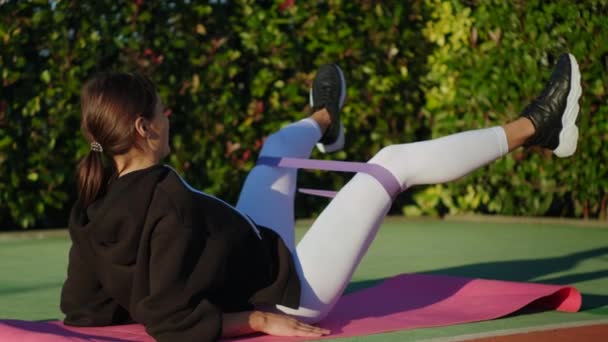 Donna sportiva durante il suo allenamento di fitness con elastico all'aperto — Video Stock