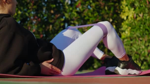 Allenamento nel parco, la donna sta allenando le gambe con elastico fitness — Video Stock
