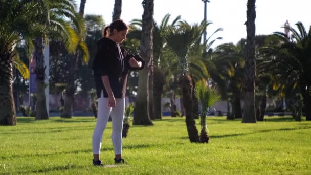 Kvinna tränar med stretchtejp i trädgården — Stockvideo