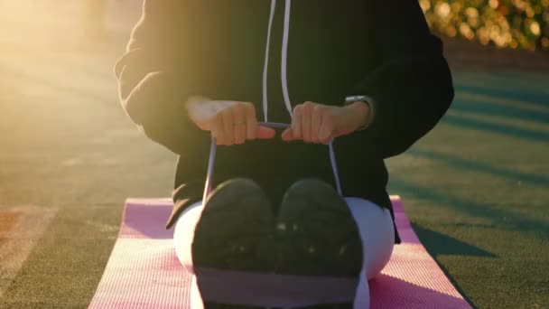 Kvinna gör fysiska övningar med fitness elastisk band utomhus — Stockvideo