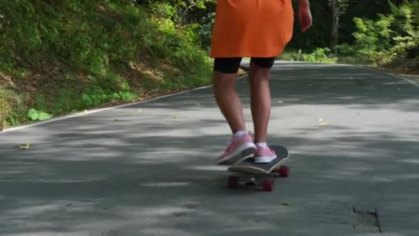 Jovem mulher desportiva é skate no verão, de pé a bordo e rolando sobre a estrada — Vídeo de Stock