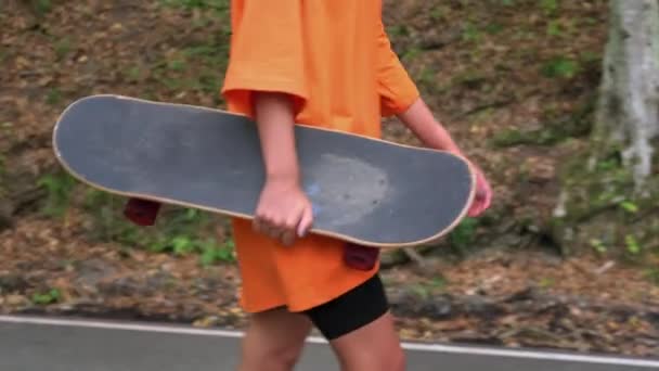 Девушка со скейтбордом выходит на улицу — стоковое видео