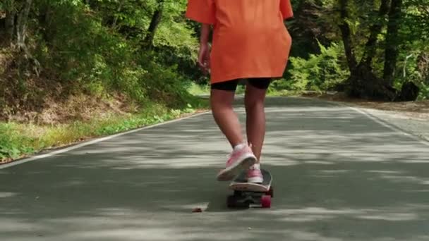 스케이트타는 여자가 여름 방학 때 숲 공원에서 스케이트보드를 타고 있다 — 비디오