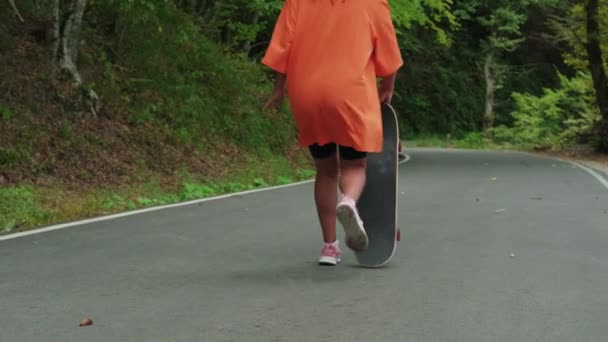 Skateboarder chica está montando monopatín al aire libre en el parque, rodando sobre la carretera, vista trasera — Vídeo de stock