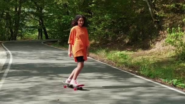Boldog tinédzser lány gördeszkázik a nyári szünetben és hétvégén — Stock videók