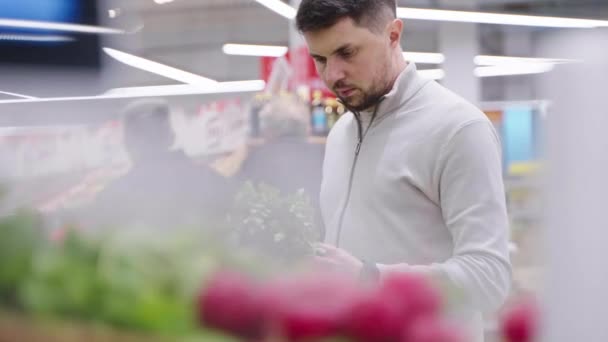 Одинокий мужчина покупает зелень в супермаркете — стоковое видео