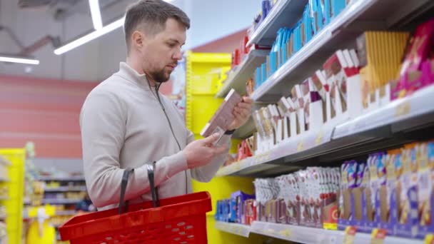 Kupiec z supermarketu kupi czekoladę. — Wideo stockowe