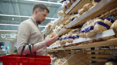 Süpermarkette ekmek reyonunda tek başına alışveriş yapan bir adam.