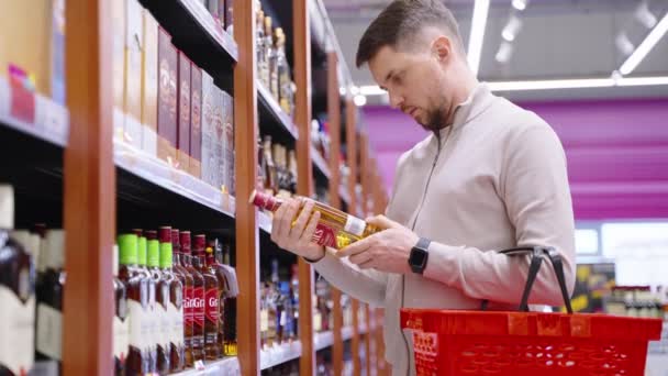 Мужчина покупает виски в супермаркете — стоковое видео