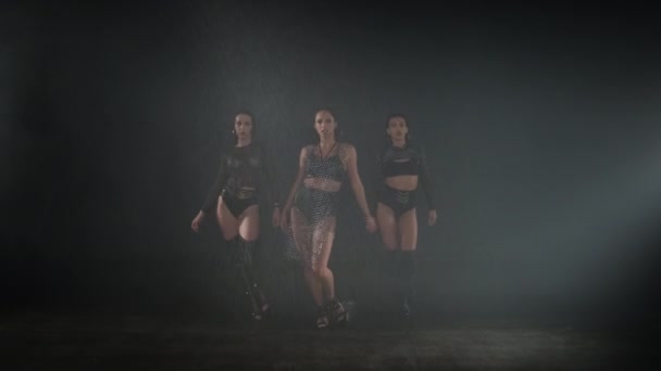 Tres mujeres bailando en estudio oscuro con lluvia falsa — Vídeos de Stock