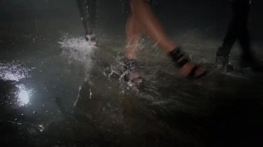 Üç dansçı kadın ıslak zeminde dans ediyor.