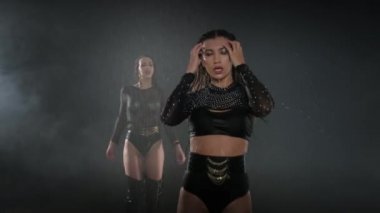 Profesyonel dansçılardan oluşan bir grup. Bayanlar, siyah arka planda tutkuyla ilerliyorlar.