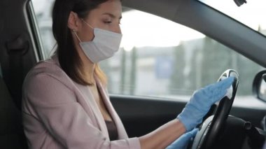 Kovid-19 enfeksiyonunu önlemek için koruyucu ekipman. Kadın direksiyonu siliyor.