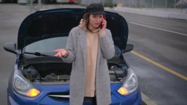 Kadın sürücü araba servisini arıyor, yolda bozuk bir arabanın yanında duruyor, sigorta şirketini arıyor.