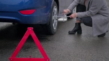 Kadın araba tekerleğiyle ilgili sorunla yüzleşiyor ama onu tamir edemiyor.