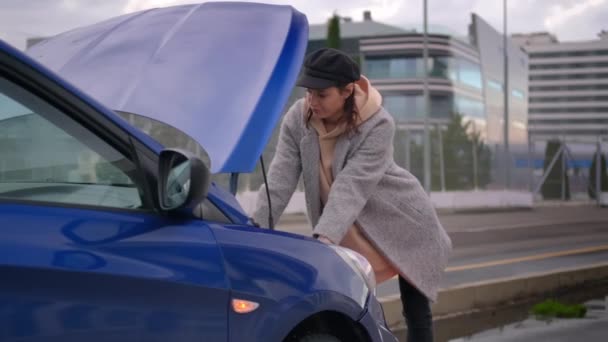 Car breakdown on the road in city, female driver is viewing to under hood space — Stock Video