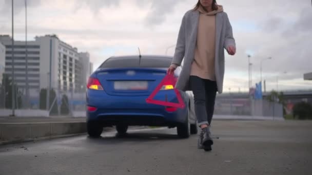 Warning triangle for warning about accident or broken car on road, female driver is putting sign — Stock Video