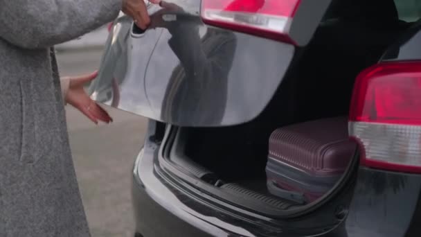 Woman opening car trunk and taking a suitcase — Stock Video