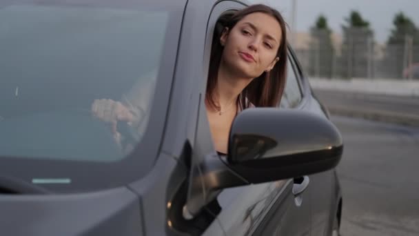 Kvinnlig bilförare kontrollerar situationen på vägen genom att luta sig ut genom fönstret — Stockvideo