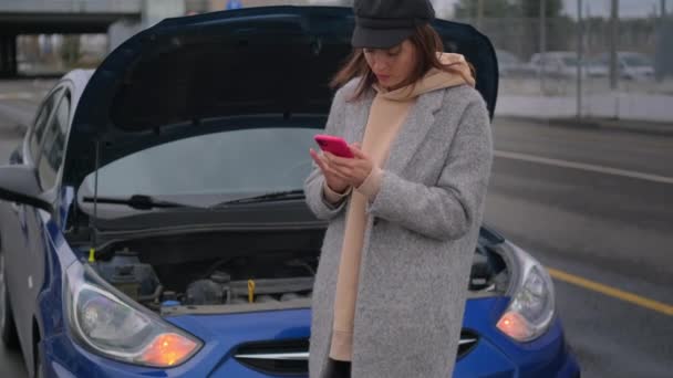 Automobile is broken on road in city, female driver is typing message by smartphone — Stock Video