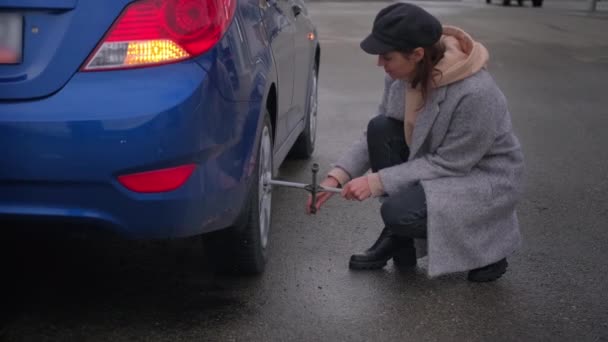 Mulher tentando lidar com problemas de roda de carro e usando chave cruzada — Vídeo de Stock