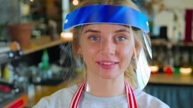 Yüz kalkanındaki gülümseyen kadın barista, COVID-19 kuralları