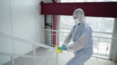 Koruyucu giysili adam tırabzanları dezenfekte ve dezenfekte ediyor.