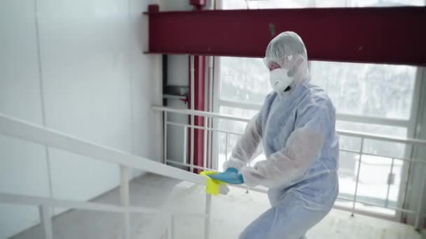 Man in protective overall is wiping handrails with sanitizer, disinfecting — Stock Video