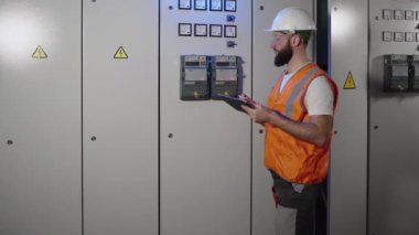 Elektrik mühendisliği uzmanı elektrik panelindeki sayacı kontrol ediyor.