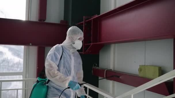 Kimyasal koruma giysisi içindeki insanlar binanın içini dezenfekte ediyor, duvarlara dezenfektan püskürtüyor. — Stok video