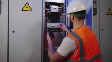Fabrikadaki endüstriyel elektrik panelinin tamiri, elektrikçi devre kesicileri kontrol ediyor.
