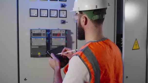 Maskinist kontrollerer målingen av det elektriske panelet og fyllerapporten i nettbrett – stockvideo