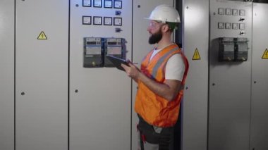Mühendis tesisteki elektrik teçhizatını kontrol ediyor.