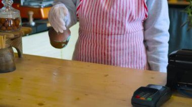 Barista, COVID-19 kahve dükkanındaki tezgahı temizlemek için dezenfektan kullanıyor.