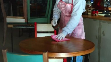 Coronavirus salgınında restoranda masanın dezenfekte edilmesi, garsonun yakın çekim görüntüsü.