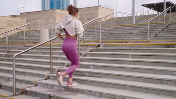 На открытом воздухе тренировки в городе, женщина бежит по лестнице, напрягая мышцы ног — стоковое видео
