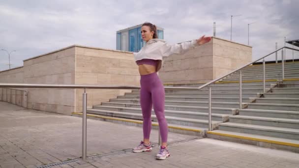 Femme sportive fait des exercices physiques à l'extérieur, réchauffant son corps avant l'entraînement — Video