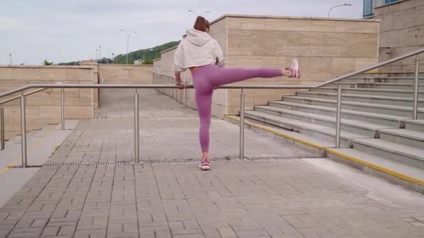 Женщина тренирует свое тело для красивой, размахивая ногами на открытом воздухе — стоковое видео