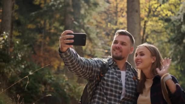 Блогеры путешественников снимают себя во время похода по лесу, делая селфи на смартфоне — стоковое видео