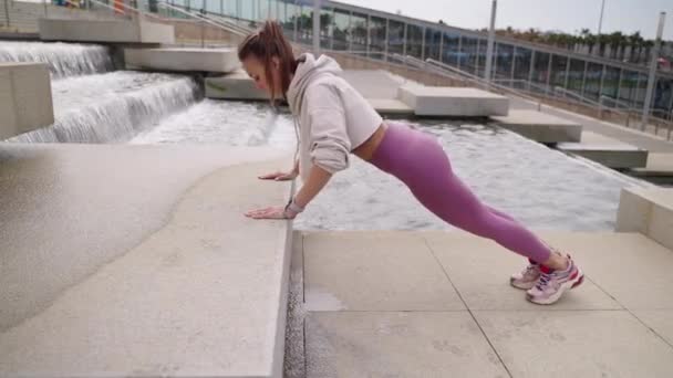 Спортивная женщина делает отжимания в городском пейзаже, здоровый образ жизни горожан — стоковое видео