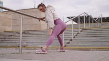 Seksi kadın çömeliyor, dışarıda antrenman yapıyor, vücut şeklini ve sağlığını önemsiyor.