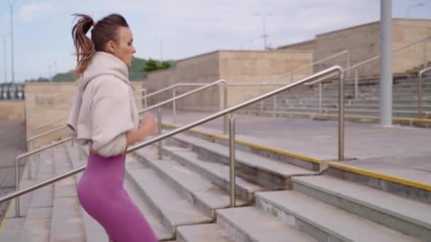 Sokak antrenmanı, genç bir kadın zinde kalmak için merdivenlerin üzerinden koşuyor. — Stok video